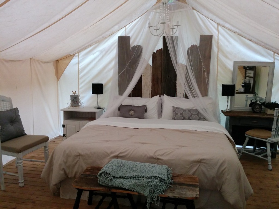 Ein stilvoll eingerichteter Schlafbereich in einem Glamping-Zelt zeigt, wie luxuriös Camping sein kann, mit bequemem Bett und geschmackvoller Dekoration.